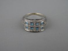 AN EIGHTEEN CARAT GOLD DRESS RING having eight square topaz stones in an oblong setting with tiny