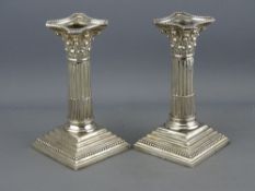 A PAIR OF SILVER CORINTHIAN COLUMN CANDLEHOLDERS (loaded), 15 cms high and each having a square