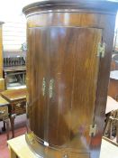 A REPRODUCTION ANTIQUE MAHOGANY BOW FRONTED TWO DOOR HANGING CORNER CUPBOARD with two interior