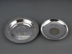 TWO SILVER WINSTON CHURCHILL COMMEMORATIVE DISHES, the centres inset with commemorative coins,