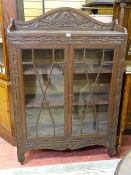 A VINTAGE CARVED OAK BOOKCASE having three quarter top rail over twin eight pane astragal glazed