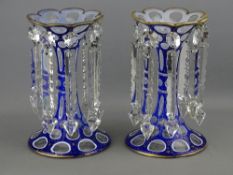 A PAIR OF ATTRACTIVE CIRCULAR BASED BLUE OVERLAID GLASS DROP LUSTRE VASES, 20 cms high