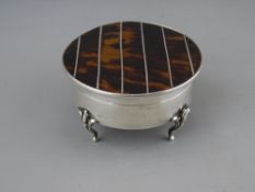 A CIRCULAR SILVER RING BOX on four supports and with a hinged silver line inlaid tortoiseshell