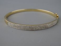A TRIPLE ROW DIAMOND & NINE CARAT GOLD BANGLE, stamped 0.75 carat diamond weight, 7 cms across, 13.5