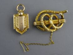 A VICTORIAN PINCHBECK OPEN WORK BROOCH and a shield shaped pendant locket