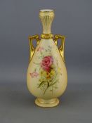 A ROYAL WORCESTER NARROW NECKED TWO HANDLED BLUSH GROUND VASE with floral posy decoration front
