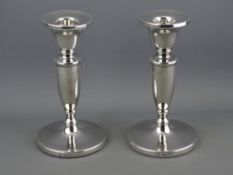 A PAIR OF SILVER CIRCULAR BASED PLAIN SHORT STEMMED CANDLEHOLDERS (loaded), 14 cms high,