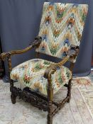 A SUBSTANTIAL CARVED CONTINENTAL WALNUT ARMCHAIR having swept arms and leaf detail to the front