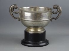 A CIRCULAR SILVER PEDESTAL SPORTING TROPHY with double scrolled handles, on a plinth, 12 troy ozs,