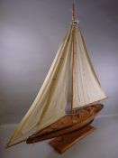 AN ATTRACTIVE WOODEN MODEL YACHT ON STAND, 106 cms high overall, 93 cms long bow to stern