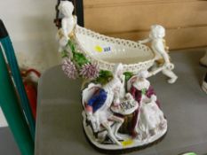 Continental cherub decorated flower basket in the form of a cart and a porcelain group of three