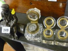 Composition figure of a gentleman sitting on a log and three glass inkwells with brass hinges