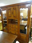 An Edwardian mahogany wardrobe, chest of drawers and linen cupboard combination with flanking