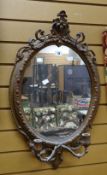 An antique gilt framed oval wall mirror with candle sconce base, 73cms high Condition reports