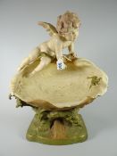 An imposing Royal Dux pottery model of a cherub gazing at a frog inside a clam over a naturalistic