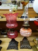 Two antique oil lamps - both with pierced metal square form bases, one with cranberry glass