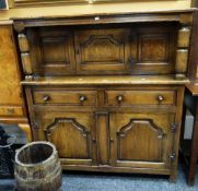 An antique reproduction panelled court cupboard, the base with two cupboards, two drawers and with