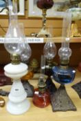 A group of five oil lamps including cranberry glass and three with metal bases Condition reports
