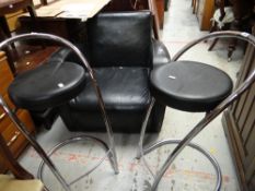 A set of four chrome and leather circular seated bar stools and a modern black leather armchair