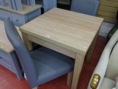 Modern light wood effect square dining table with fold-out section and two grey upholstered dining