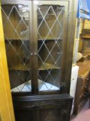 Standing corner cupboard with twin glazed upper doors over carved base doors