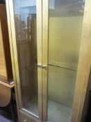 Light wood two door glazed display cabinet with lower drawer