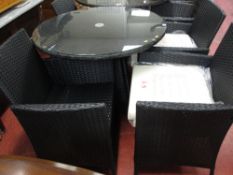 Black rattan patio set comprising circular table with glass top and four armchairs