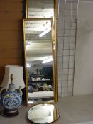 Two long gilt framed mirrors and a bevelled edge oval example