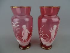 Pair of cranberry glass Mary Gregory style decorated vases, 14 cms high