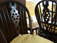 In the manner of Ercol, a dark stained drop leaf dining table and four matching wheel back chairs