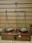 A set of W & T Avery brass provision scales standing on a mahogany base with single drawer