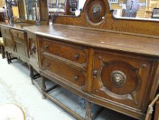 A vintage oak railback sideboard with two centre drawers and the flanking cupboards having lion head