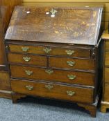 An antique oak bureau with sloped front and chest base of two long, two short and upper shallow