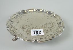 A George II silver salver on three-pad feet and of scalloped form and bearing centred heraldic