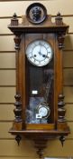An antique Vienna-type wall clock having a circular white enamel dial bearing Roman numerals