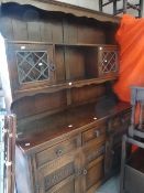 A good reproductiom Jaycee linenfold-style oak dresser with leaded door top and three-cupboard base