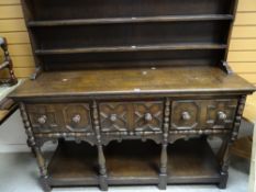 A vintage oak Jacobean-style dresser having an open rack and moulded and carved three-drawer base,