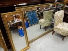 A LARGE GILT WOOD WALL MIRROR together with similar gilt framed bevelled hall mirror