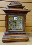 A GERMAN WALNUT ENCASED MANTEL CLOCK having a brass dial with silvered chapter ring bearing Roman