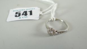 DIAMOND RING being an 18-carat white gold diamond cluster ring with diamond chip shoulders in ring