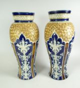 A PAIR OF DOULTON LAMBETH VASES of slender baluster form, decorated with cobalt blue panel reserves,