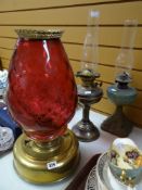 THREE OIL LAMPS, one standing on a large brass reservoir