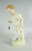 AN IRRIDESCENT PORCELAIN FIGURE OF A CHILD KICKING A FOOTBALL on a naturalistic base in the manner