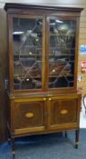 AN EDWARDIAN INLAID MAHOGANY BOOKCASE CUPBOARD having a two-door glazed top and two-cupboard base on