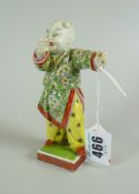 JAPANESE PORCELAIN FIGURE OF A PERFORMING CLOWN in Prunus Kimono and yellow pyjamas, standing on a