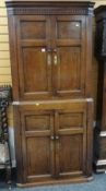 ANTIQUE OAK TWO SECTION BLIND PANEL CORNER CUPBOARD, both sections revealing fitted shaped shelves