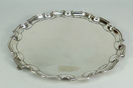 GEORGE V SILVER SALVER having pie crust edge raised on three scroll-type feet, Birmingham 1932,