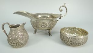 THREE PIECES OF BELIEVED INDIAN SILVER comprising scroll-handled sauce boat decorated with deities
