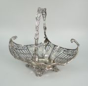 EDWARD VII SILVER PIERCED SWING-HANDLED BASKET of scroll decoration raised on four scroll feet,