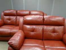 A RED LEATHER EFFECT LOUNGE SUITE comprising reclining two and three seater sofas